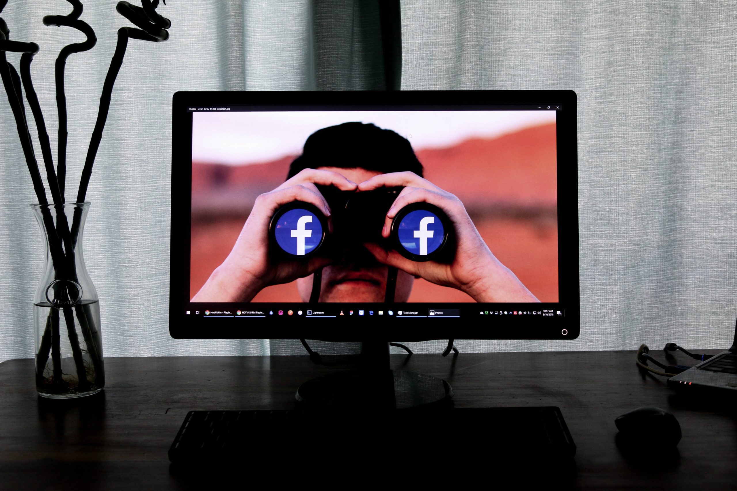 Immagine di un uomo nel computer che guarda dal cannocchiale con le icone logo di Facebook, Meta Inc.